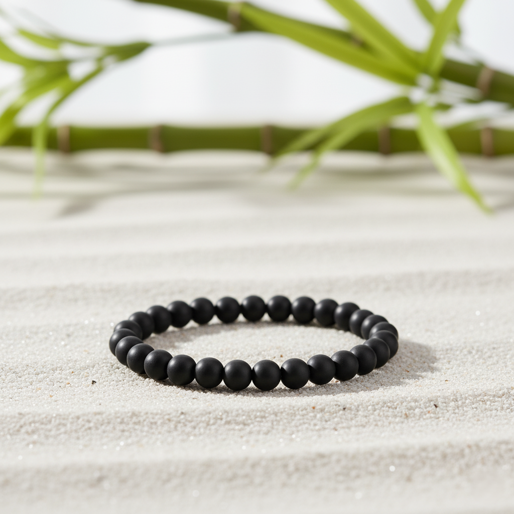 Karungali Bracelet on sandy surface with green bamboo, symbolizing protection and prosperity.